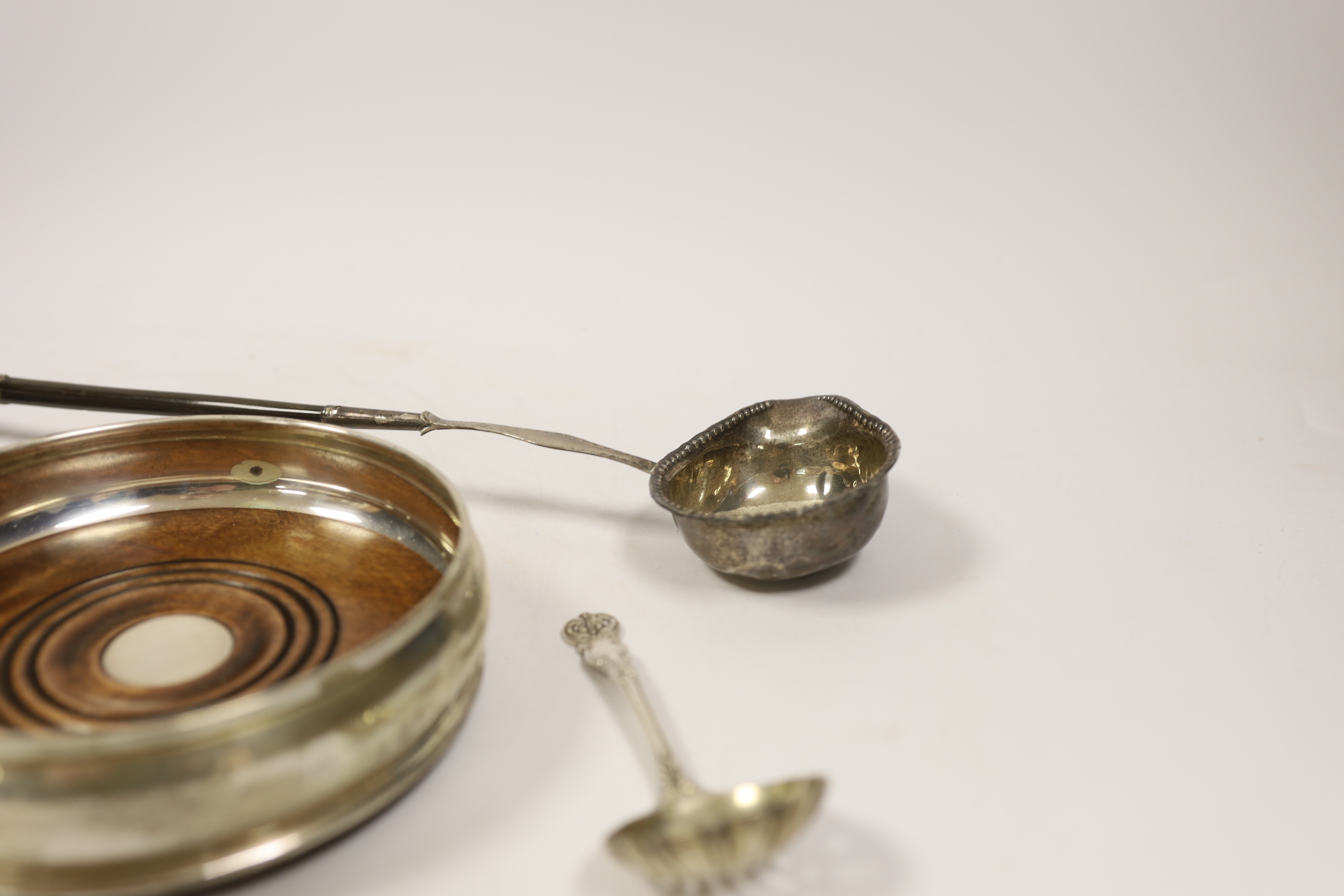 A modern silver mounted wine coaster, a silver sifter spoon, sterling cigarette case, silver tobacco box and a white metal toddy ladle with baleen handle.